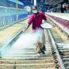 Woman Spraying Powder at Railway Tracks